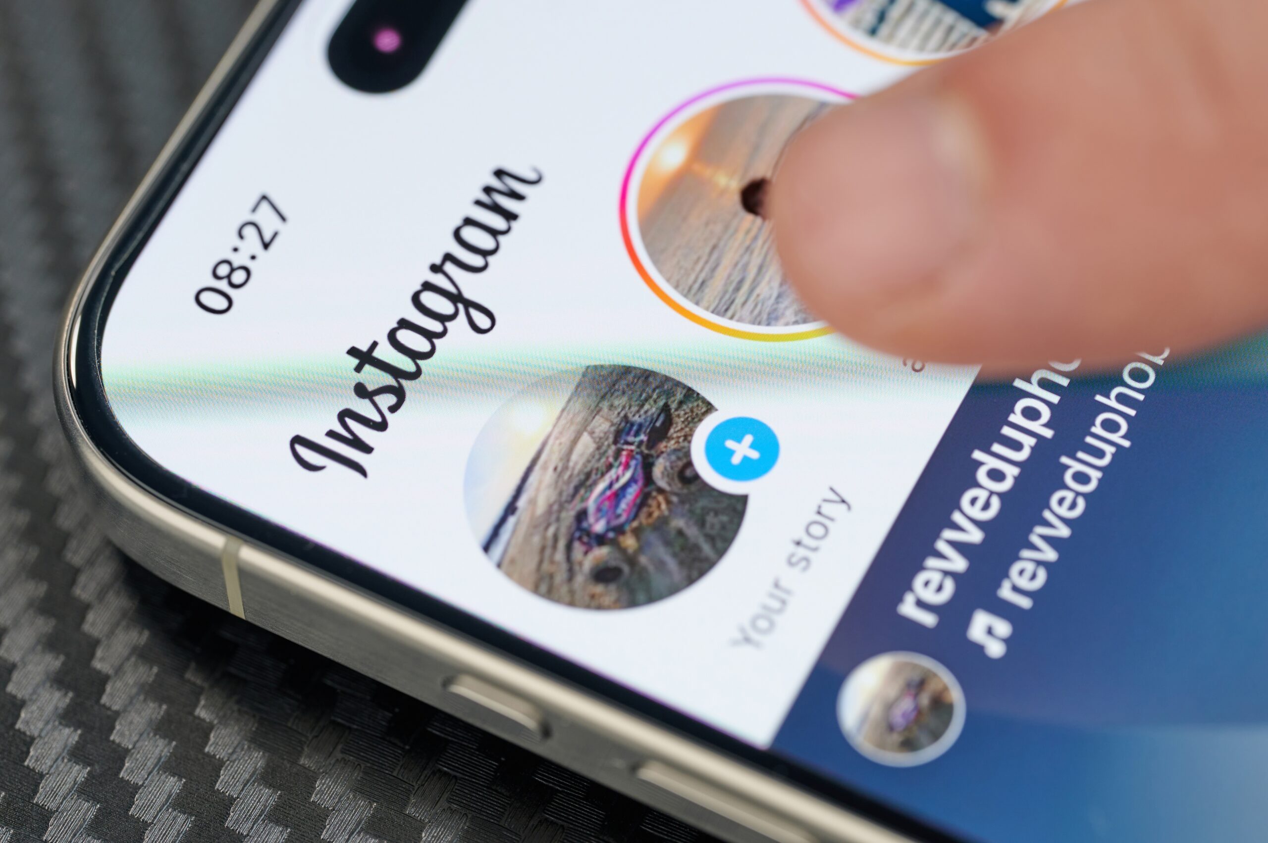 Close-up of a smartphone displaying the Instagram app with a finger tapping a profile story.