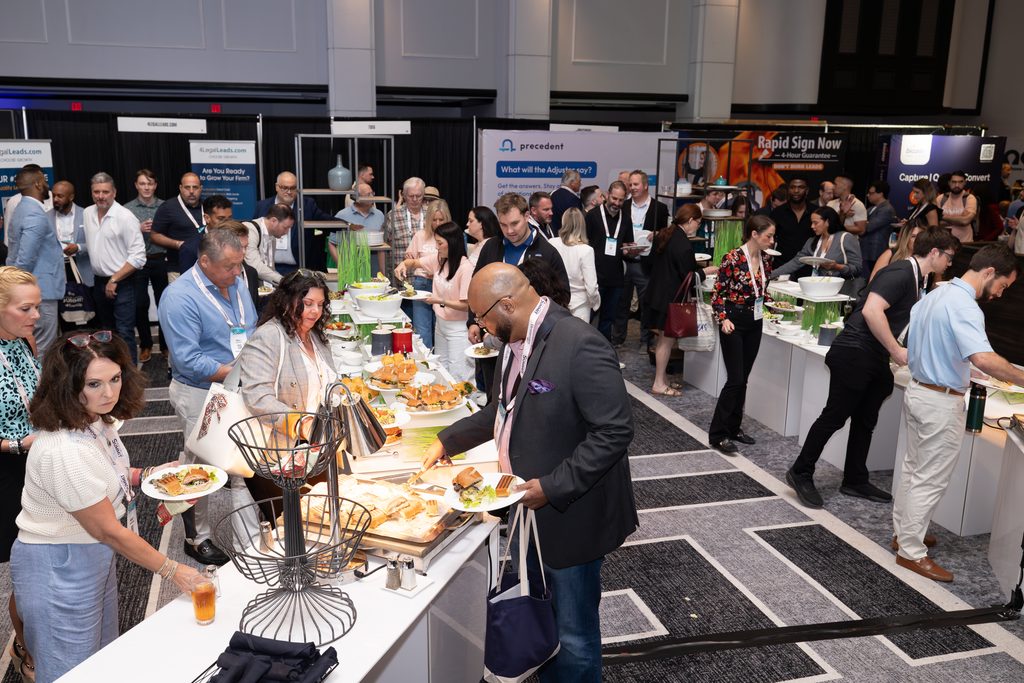Conference attendees networking and enjoying refreshments in a busy legal industry exhibit hall.