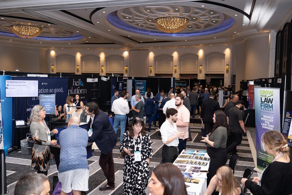 Legal professionals and exhibitors networking throughout a large conference exhibit hall lined with vendor booths.