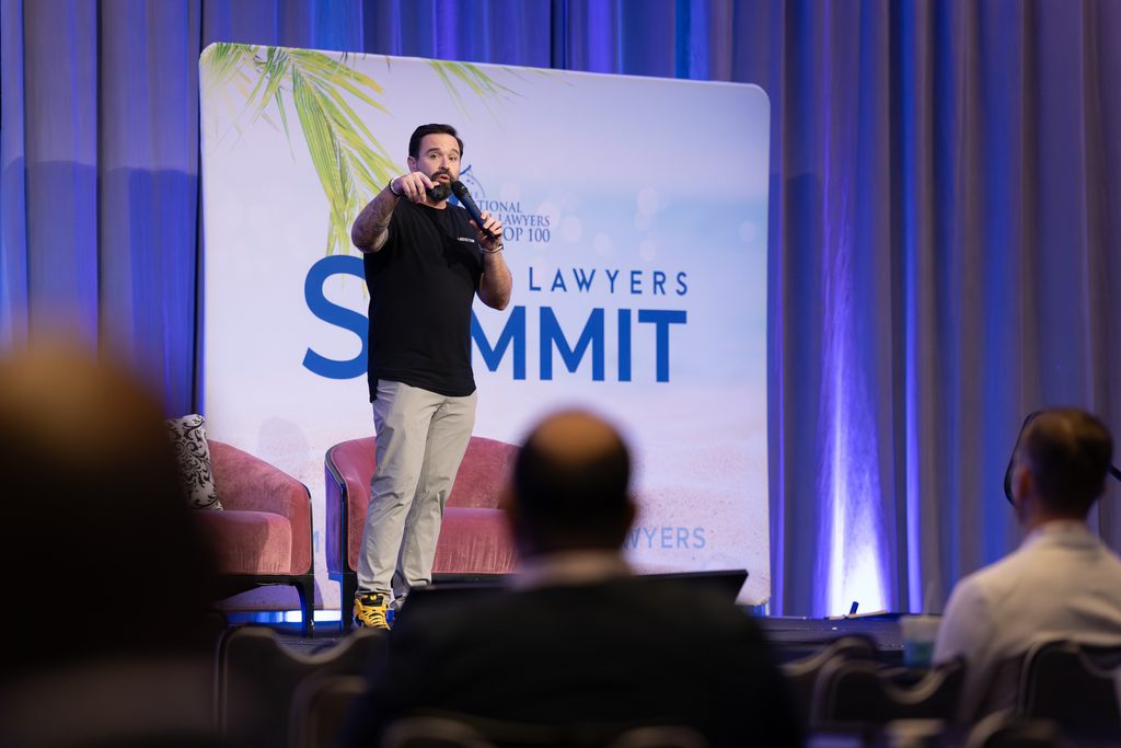 Speaker presenting on stage to an audience during the National Trial Lawyers Summit.